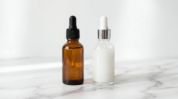 Two skincare serum bottles side by side on white marble—amber vitamin C serum and clear niacinamide serum—showing they can be used together